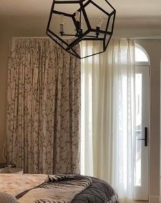 Stylish bedroom window treatment with floral drapery and light curtains, showcasing elegant design and function.