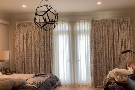 Stylish bedroom window treatment with floral drapery and light curtains, showcasing elegant design and function.