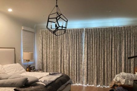 Stylish bedroom window treatment with floral drapery and light curtains, showcasing elegant design and function.
